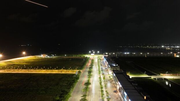 Aerial view of Pantai Indah Kapuk 2 at night featuring a lit road with vehicle light trails modern buildings and surrounding land in Kecamatan Penjaringan Banten Indonesia. Aerial view of Pantai Indah Kapuk 2 at night featuring a lit road with vehicle light trails modern buildings and surrounding land in Kecamatan Penjaringan Banten Indonesia.
