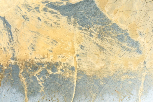 Aerial view of the abstract textures and mineral deposits of the Minas de Riotinto with cracked earth and yellow hues in Minas de Riotinto Andalusia Spain.