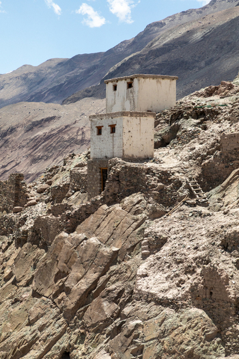 View of the historic Charasa Gonpa monastery perched on a rugged rocky hillside featuring traditional white washed stone walls and wooden window frames in Charasa Ladakh India.