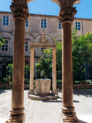 View of the historic stone well and ornate columns in the courtyard of a monastery within Dubrovnik Old Town Dubrovnik Dubrovnik Neretva County Croatia. View of the historic stone well and ornate columns in the courtyard of a monastery within Dubrovnik Old Town Dubrovnik Dubrovnik Neretva County Croatia.