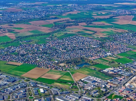 Aerial view of patchwork fields meet urban sprawl a tapestry of greens and browns contrasting with the dense housing Sausheim Grand Est France.