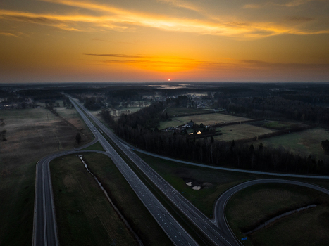 Aerial view of the highway interchange between the A5 and A8 roads at sunrise with surrounding fields and forests in Olaine parish Olaine Municipality Latvia. Aerial view of the highway interchange between the A5 and A8 roads at sunrise with surrounding fields and forests in Olaine parish Olaine Municipality Latvia.