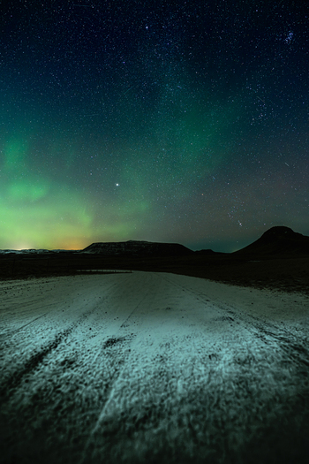 View of the ethereal green aurora borealis dances above the snowy landscape casting an otherworldly glow on the horizon Krysuvikurkirkja Hafnarfjardarkaupstadur Iceland.