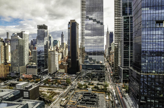 Aerial view of Hudson Yards in Manhattan with modern glass skyscrapers urban streets and the Empire State Building in the distance New York New York United States.
