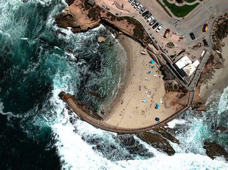 Aerial view of La Jolla Cove featuring the Children s Pool sea wall crashing turquoise waves and people on the sandy beach in San Diego California United States. Aerial view of La Jolla Cove featuring the Children s Pool sea wall crashing turquoise waves and people on the sandy beach in San Diego California United States.