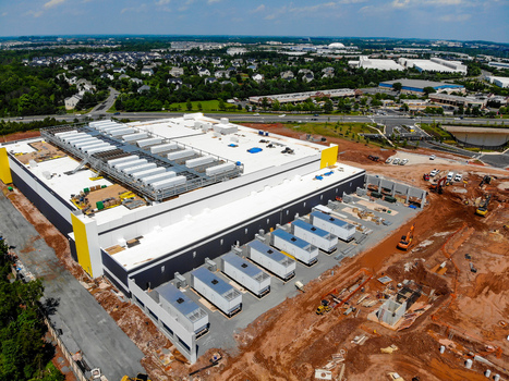 Aerial view of a large data center construction site with industrial equipment red soil and surrounding suburban infrastructure in Ashburn Virginia United States. Aerial view of a large data center construction site with industrial equipment red soil and surrounding suburban infrastructure in Ashburn Virginia United States.