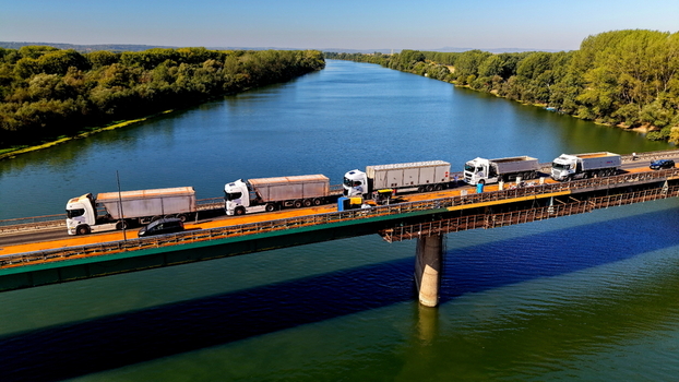 Aerial view of trucks driving across the bridge over the Danube river near the shipyard in Smederevo Podunavlje District Serbia.