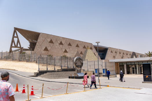 Giza Egypt 16 May 2026 View of the Grand Egyptian Museum featuring its modern triangular facade with people walking in the foreground under a clear sky.