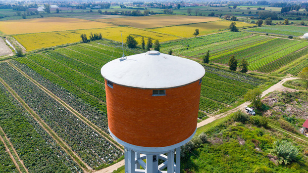 Aerial view of the Torre dell Acquedotto Gruppo CAP water tower surrounded by lush green agricultural fields and farmland in Mediglia Lombardy Italy.