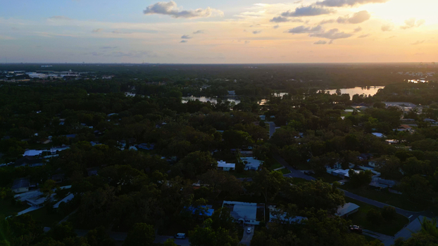 Aerial view of a residential neighborhood in Tampa Florida United States featuring lush green trees scattered houses and a serene lake reflecting the warm glow of the sunset. Aerial view of a residential neighborhood in Tampa Florida United States featuring lush green trees scattered houses and a serene lake reflecting the warm glow of the sunset.