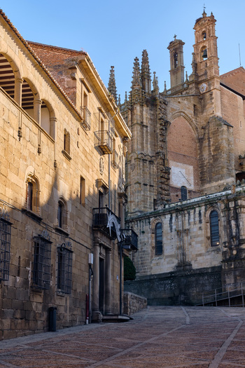 Plasencia Spain 03 December 2025 View of the Catedral Nueva de Plasencia with its ornate Gothic spires seen from a cobblestone street lined with historic stone buildings. Plasencia Spain 03 December 2025 View of the Catedral Nueva de Plasencia with its ornate Gothic spires seen from a cobblestone street lined with historic stone buildings.