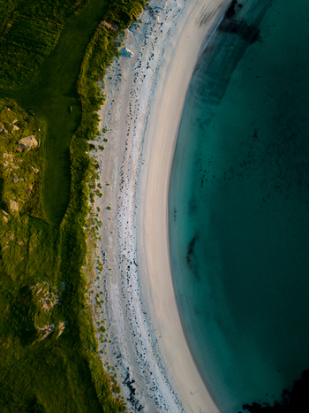 Aerial view of a white sandy beach meeting turquoise ocean water and lush green coastal vegetation in Leknes Nordland Norway. Aerial view of a white sandy beach meeting turquoise ocean water and lush green coastal vegetation in Leknes Nordland Norway.