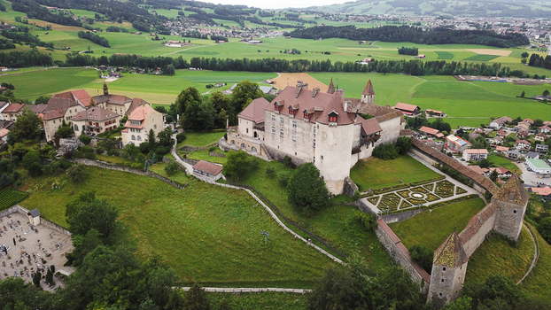 Aerial view of Chateau de Gruyeres with its medieval stone walls formal gardens and surrounding green pastures in Gruyeres Fribourg Switzerland.