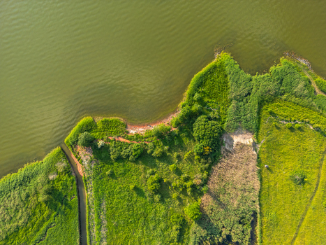Aerial view of Vistula Lagoon coastline with lush green meadows dense vegetation and a small inlet Tolkmicko Warmian Masurian Voiv Poland. Aerial view of Vistula Lagoon coastline with lush green meadows dense vegetation and a small inlet Tolkmicko Warmian Masurian Voiv Poland.