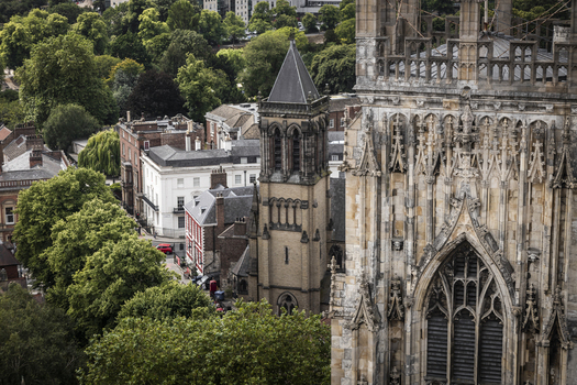 Aerial view of the historic York Minster and surrounding stone buildings nestled among lush green trees in the city center York England United Kingdom.