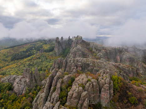 Aerial view of the unique sandstone and conglomerate rock formations of the Belogradchik Rocks surrounded by autumn forests and low hanging clouds in Belogradchik Vidin Bulgaria. Aerial view of the unique sandstone and conglomerate rock formations of the Belogradchik Rocks surrounded by autumn forests and low hanging clouds in Belogradchik Vidin Bulgaria.