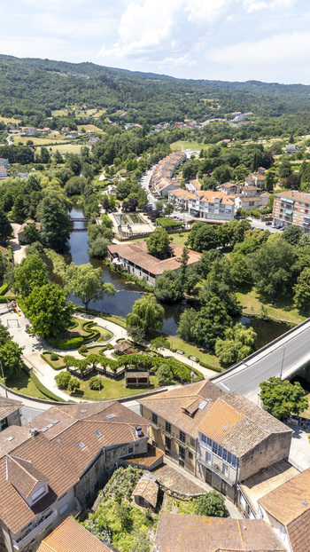 Aerial view of the town of Allariz with the Arnoia river flowing through lush green parks and historic stone buildings with terracotta rooftops in Allariz Province of Ourense Spain. Aerial view of the town of Allariz with the Arnoia river flowing through lush green parks and historic stone buildings with terracotta rooftops in Allariz Province of Ourense Spain.
