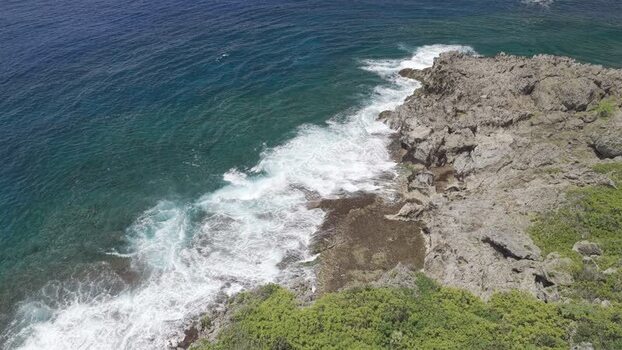 Aerial view of waves crashing on rocky shores of Siargao Philippines.