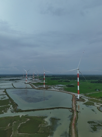 Aerial view of the Khurushkul wind farm featuring red and white striped turbines rising above flooded wetlands and lush green fields in Cox s Bazar Chittagong Division Bangladesh. Aerial view of the Khurushkul wind farm featuring red and white striped turbines rising above flooded wetlands and lush green fields in Cox s Bazar Chittagong Division Bangladesh.