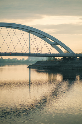 View of Zezelj Bridge spanning the Danube River at sunset with soft light reflecting on the water in Novi Sad Vojvodina Serbia. View of Zezelj Bridge spanning the Danube River at sunset with soft light reflecting on the water in Novi Sad Vojvodina Serbia.