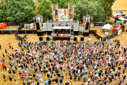 Herzogenaurach Germany 22 July 2022 Aerial view of the Open Beatz Festival stage with a large crowd of people dancing in front of the rustic industrial structure. Herzogenaurach Germany 22 July 2022 Aerial view of the Open Beatz Festival stage with a large crowd of people dancing in front of the rustic industrial structure.