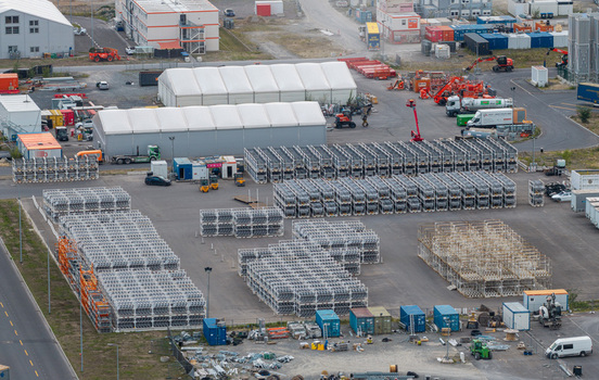 Aerial view of the Tesla Gigafactory Berlin Brandenburg site with stacked metal frames shipping containers and construction equipment in Grunheide Mark Brandenburg Germany. Aerial view of the Tesla Gigafactory Berlin Brandenburg site with stacked metal frames shipping containers and construction equipment in Grunheide Mark Brandenburg Germany.