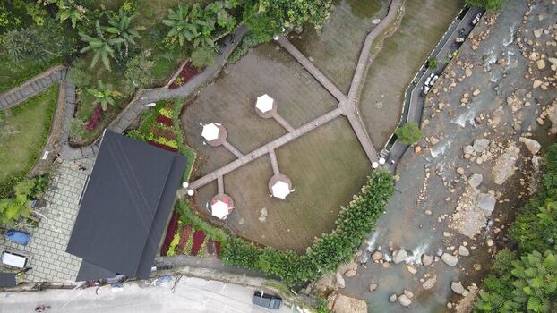 Aerial view of Kopi Tubing Cafe and Resto featuring wooden walkways white umbrellas lush greenery and a flowing river in Kecamatan Pamijahan Jawa Barat Indonesia. Aerial view of Kopi Tubing Cafe and Resto featuring wooden walkways white umbrellas lush greenery and a flowing river in Kecamatan Pamijahan Jawa Barat Indonesia.
