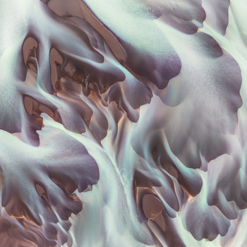 Aerial view of a complex braided river system with intricate glacial sediment patterns flowing through the landscape of Iceland. Aerial view of a complex braided river system with intricate glacial sediment patterns flowing through the landscape of Iceland.