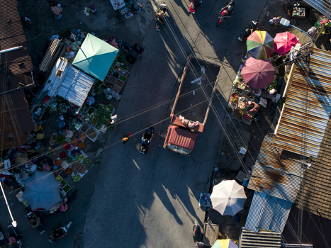 Aerial view of a bustling street market with a red truck motorbikes and colorful stalls under morning light in Kemalang Central Java Indonesia.