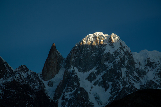 View of the snow capped Lady Finger peak illuminated by golden sunlight against a dark blue sky Hunza Nagar Gilgit Pakistan. View of the snow capped Lady Finger peak illuminated by golden sunlight against a dark blue sky Hunza Nagar Gilgit Pakistan.