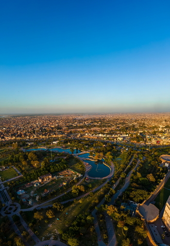Aerial view of Minar e Pakistan surrounded by lush parklands winding water features and the expansive urban cityscape under a clear blue sky in Lahore Punjab Pakistan.