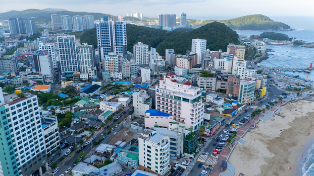 Aerial view of the coastal district of Songjeong dong featuring high rise residential buildings hotels a sandy beach and a harbor in Busan Busan South Korea. Aerial view of the coastal district of Songjeong dong featuring high rise residential buildings hotels a sandy beach and a harbor in Busan Busan South Korea.