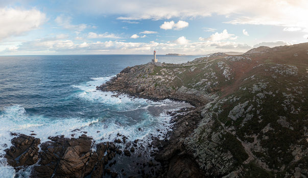 Aerial view of Faro de Punta Nariga lighthouse standing on a rugged rocky cliff with crashing waves and a cloudy sky Malpica A Coruna Spain. Aerial view of Faro de Punta Nariga lighthouse standing on a rugged rocky cliff with crashing waves and a cloudy sky Malpica A Coruna Spain.