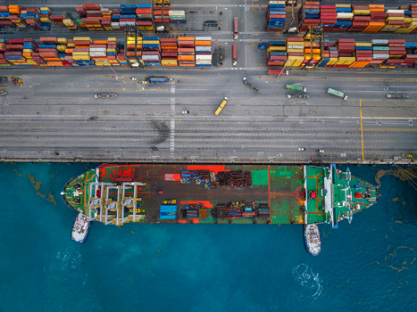 Aerial view of Caucedo Logistics Center featuring a cargo ship docked at the pier colorful shipping containers and trucks on the terminal in Andres Santo Domingo Dominican Republic. Aerial view of Caucedo Logistics Center featuring a cargo ship docked at the pier colorful shipping containers and trucks on the terminal in Andres Santo Domingo Dominican Republic.