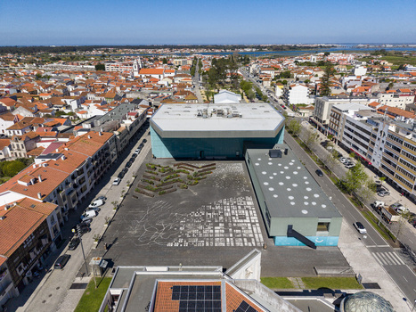 Aerial view of a bold modern building and its textured plaza standing out against the dense red tiled cityscape Ilhavo Aveiro Portugal. Aerial view of a bold modern building and its textured plaza standing out against the dense red tiled cityscape Ilhavo Aveiro Portugal.