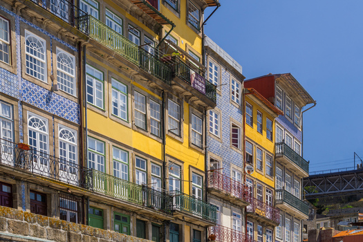 Aerial view of vibrant Ribeira houses with intricate blue tilework and colorful facades lining the Douro River under a clear sky Porto Porto District Portugal. Aerial view of vibrant Ribeira houses with intricate blue tilework and colorful facades lining the Douro River under a clear sky Porto Porto District Portugal.