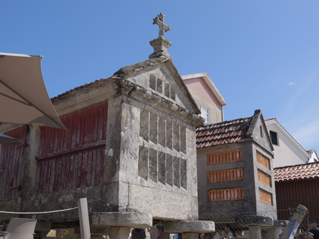View of traditional stone horreos with red wooden doors and stone crosses in the historic village of Combarro Pontevedra Spain.