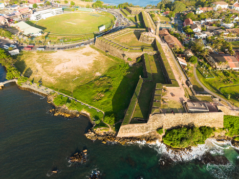 Aerial view of the historic Galle Fort ramparts and the adjacent cricket stadium along the turquoise coastline in Galle Southern Province Sri Lanka.