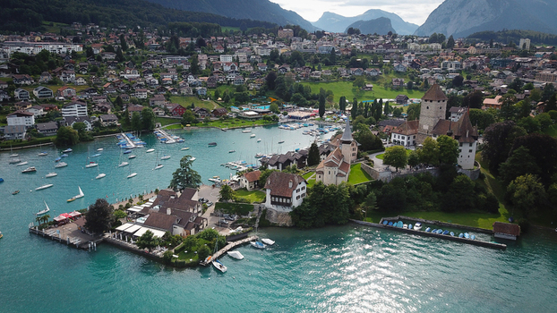 Aerial view of Schloss Spiez and the historic church on a peninsula overlooking the harbor and Lake Thun with mountains in the background Spiez Bern Switzerland. Aerial view of Schloss Spiez and the historic church on a peninsula overlooking the harbor and Lake Thun with mountains in the background Spiez Bern Switzerland.