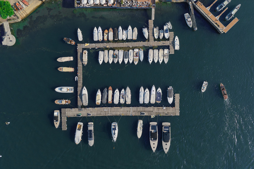 Aerial view of the marina in Lake Como with numerous docked motorboats and yachts arranged along wooden piers in the clear blue water of Como Lombardy Italy.