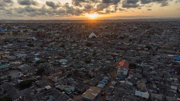 Aerial view of the Teshie neighborhood with dense residential rooftops church buildings and narrow streets under a dramatic sunset sky in Accra Greater Accra Region Ghana.