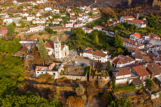 Aerial view of the historic village and the Igreja Matriz de Coja surrounded by white houses with orange rooftops and green trees Coja Coimbra District Portugal. Aerial view of the historic village and the Igreja Matriz de Coja surrounded by white houses with orange rooftops and green trees Coja Coimbra District Portugal.