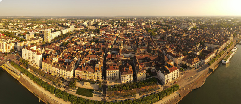 Aerial view of the historic city with dense urban rooftops a winding river and a docked river cruise ship under warm light in Chalon sur Saone Bourgogne Franche Comte France.