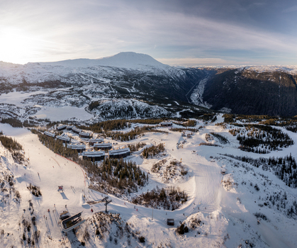 Aerial view of Gaustablikk Fjellresort nestled in the snowy mountains with ski slopes pine forests and a frozen lake under a bright winter sky in Rjukan Telemark Norway. Aerial view of Gaustablikk Fjellresort nestled in the snowy mountains with ski slopes pine forests and a frozen lake under a bright winter sky in Rjukan Telemark Norway.