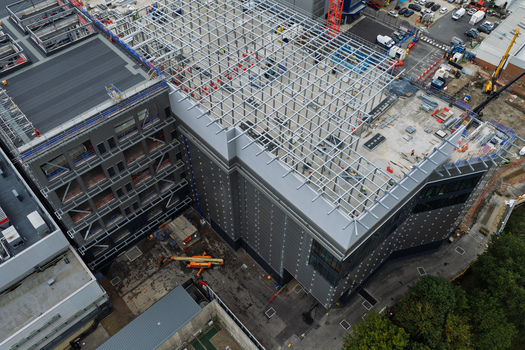 Aerial view of a data center construction site featuring a large steel framework structure grey metal cladding and heavy machinery on the ground in the United Kingdom.