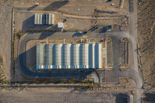 Aerial view of a large industrial building with a corrugated roof paved access roads and parking areas in the desert Enterprise Nevada United States. Aerial view of a large industrial building with a corrugated roof paved access roads and parking areas in the desert Enterprise Nevada United States.