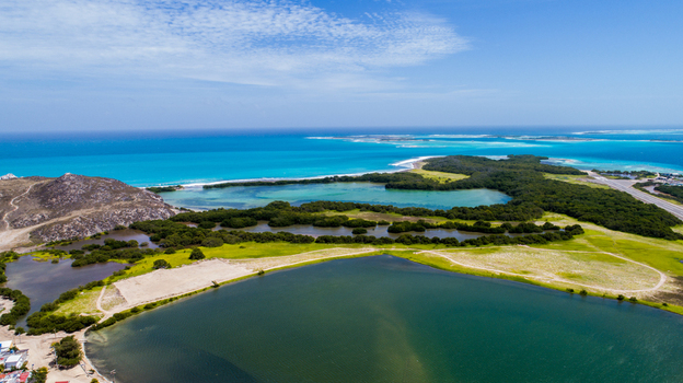 Aerial view of Los Roques archipelago featuring turquoise waters lush green mangroves and coastal lagoons under a clear blue sky in Los Roques Dependencias Federales Venezuela. Aerial view of Los Roques archipelago featuring turquoise waters lush green mangroves and coastal lagoons under a clear blue sky in Los Roques Dependencias Federales Venezuela.