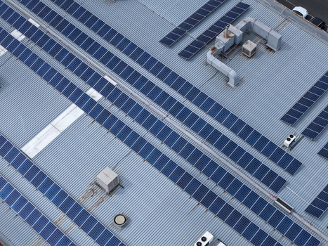 Aerial view of solar panels installed on a corrugated metal industrial rooftop with HVAC units in Melbourne VIC Australia.