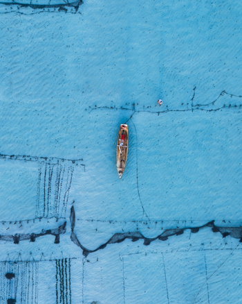 Aerial view of a weathered boat adrift on the aquamarine sea the textures of the water contrasting with the boat s faded colors Lembongan Bali Indonesia. Aerial view of a weathered boat adrift on the aquamarine sea the textures of the water contrasting with the boat s faded colors Lembongan Bali Indonesia.