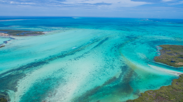 Aerial view of Los Roques archipelago featuring vibrant turquoise Caribbean waters coral reefs and small sandy cays under a clear blue sky in Los Roques Dependencias Federale Venezuela. Aerial view of Los Roques archipelago featuring vibrant turquoise Caribbean waters coral reefs and small sandy cays under a clear blue sky in Los Roques Dependencias Federale Venezuela.